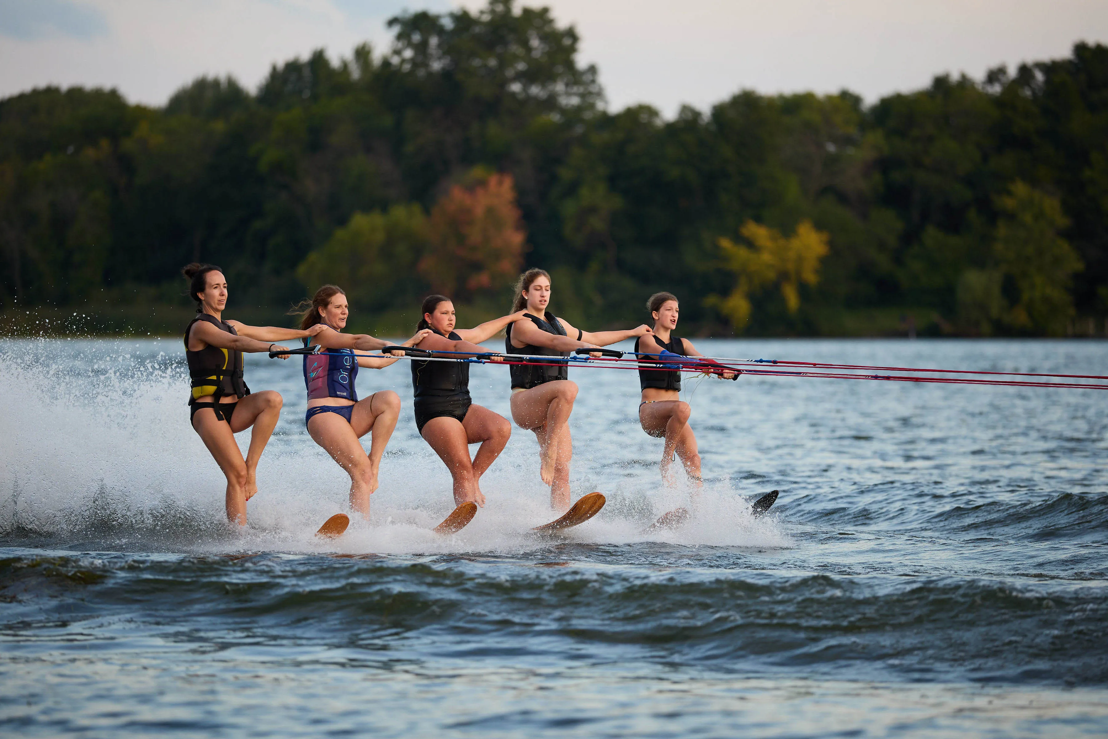 Five women waterskiing in formation on Lake Minnewashta