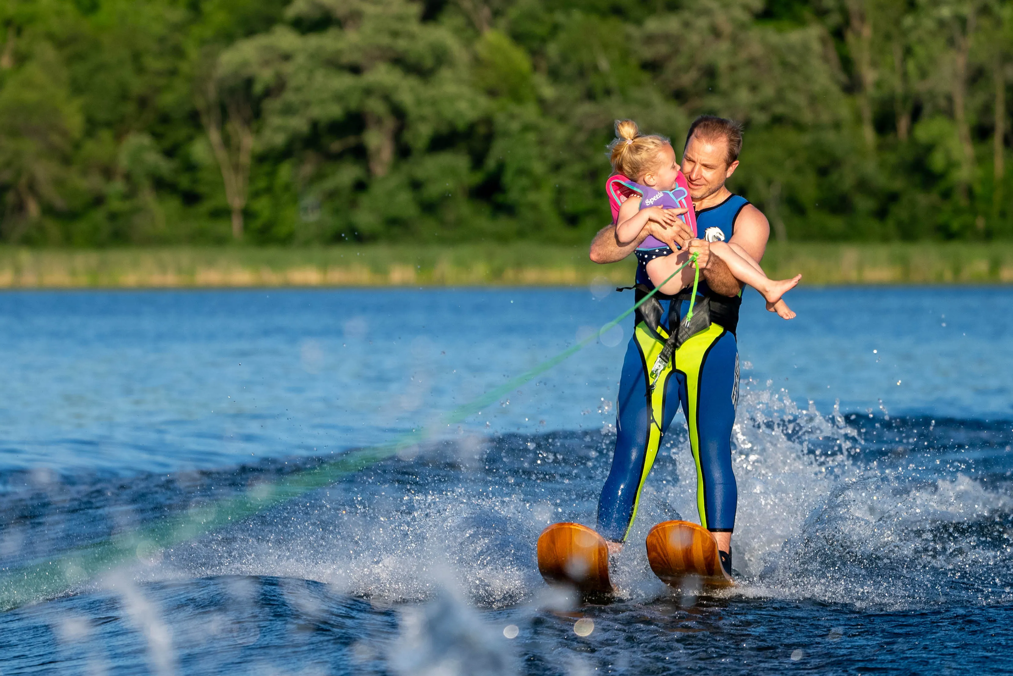 Dad waterskiing with toddler in patriotic outfit on Lake Minnewashta
