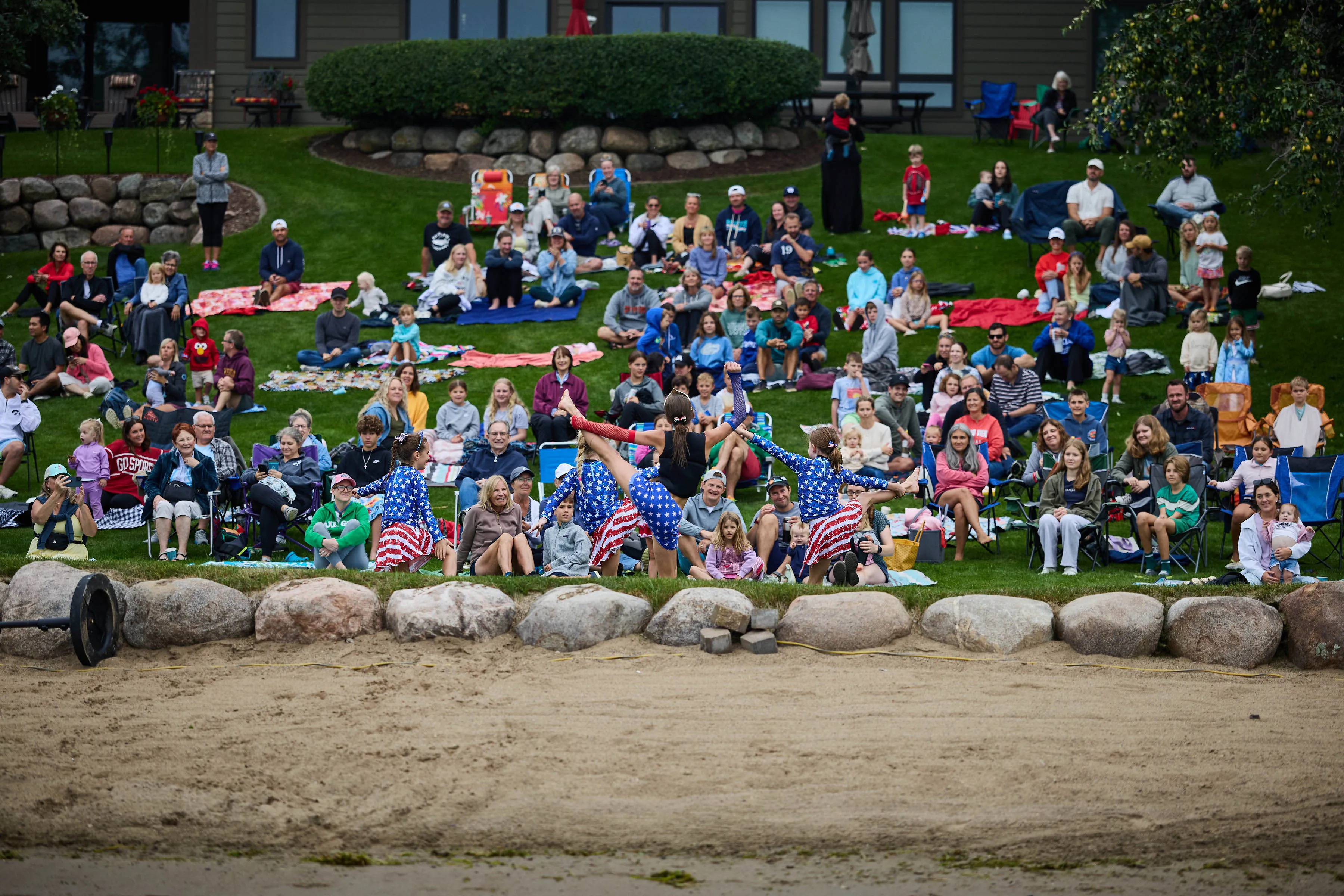 Crowd gathered on shore watching waterski performers in patriotic costumes